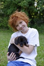 Boy holding wire-haired dachshund puppy in his arms
