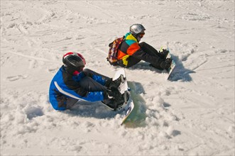 Two young snowboarders are preparing for a ski-run