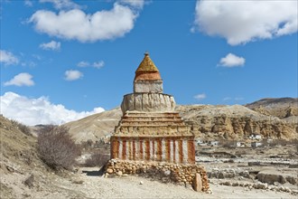 Colourfully decorated Buddhist stupa on a track in a vast landscape