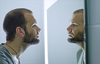 Man with a beard looking into a mirror