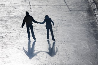 Man and woman holding hands ice skating