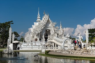 Ornate bridge with tourists to the entrance of Wat Rong Khun