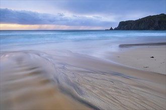 Water flows over bizarre structures on the sandy beach