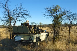 Rangers and tourists in an SUV deer-stalking in the Madikwe Game Reserve