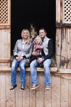 Young family sitting in the hay barn