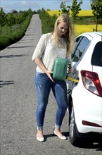 Woman filling petrol into her car from a petrol can