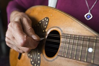 Hand of an elderly woman playing a mandolin