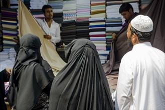 Two Muslim women and a man buying material at Mangaldas Market