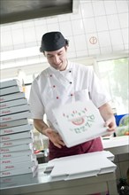 Pizza baker folding a pizza box