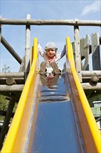 Little girl sitting on top of a slide