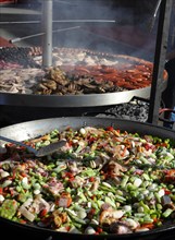Large pan containing ingredients for the paella in front of a giant barbecue at the annual All Saints Market in Cocentaina