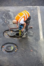 Road construction worker connecting a hydrant for water supply of the construction site