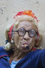 Old woman wearing coulorful clothes posing with a cigar