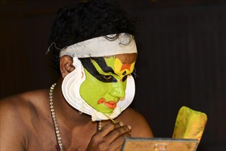 Kathakali dancer applying makeup in preparation for his performance