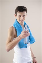 Smiling young man after doing sport holding a water bottle in his hand