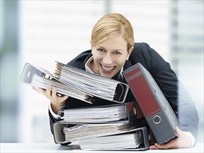Smiling business woman holding a stack of folders