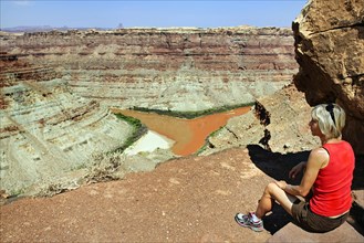 Hiker sitting at the confluence of Green River and the Colorado River in the Needles district
