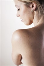 Young woman looking over her bare shoulder
