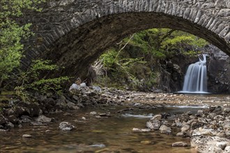 Waterfall behind an old stone bridge