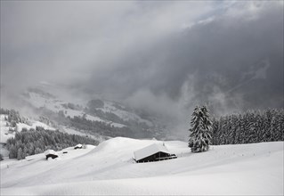 Snowed-in mountain huts on a slope with snowfall