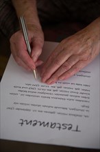 Hands of a 82-year-old woman signing a will