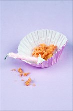 Empty cupcake or muffin case with crumbs and candle