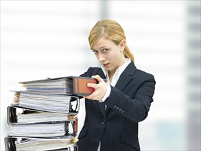 Young business woman piling up folders