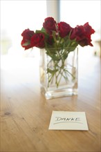 Red roses in vase with the note 'danke'