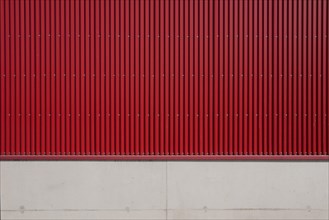 Wall of a factory building with red corrugated iron and concrete