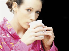Woman wearing a bathrobe drinking coffee