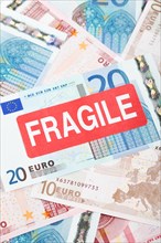 Euro banknotes with a 'Fragile' sticker