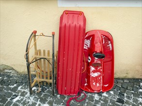 Various sledges leaning against a house wall