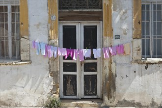 Clothesline with pink underwear hanging out to dry in front of an old door