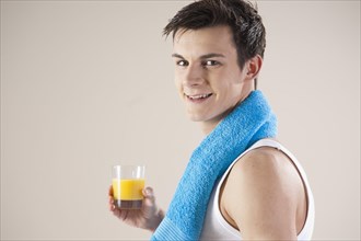 Smiling young man after doing sport holding a glass of juice in his hand