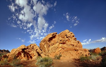 Red sandstone formation with blue cloudy sky in morning light
