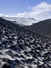 Ash-covered snowfield with the Eyjafjallajokull on the long-distance hiking trail from Skogar via Fimmvorouhals to the Thorsmork mountain ridge
