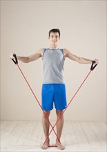 Young man doing strengthening and stretching exercises with a rubber rope