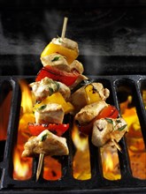 Chicken skewers being cooked over open flames