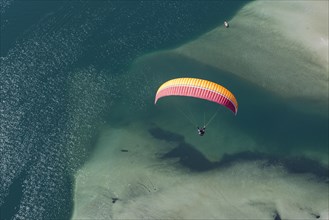 Paraglider over the Maggia river delta with naturally formed water and rocks terrain