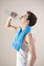 Young man quenches his thirst with a bottle of water after doing sport
