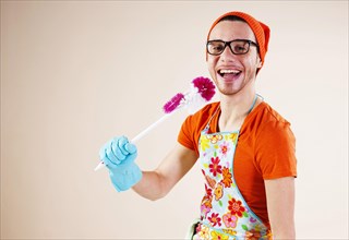 Young man holding a toilet brush in his hand while doing the housework
