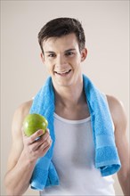 Smiling young man after doing sport holding an apple in his hand