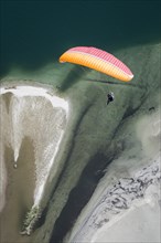 Paraglider over the Maggia river delta with naturally formed water and rocks terrain