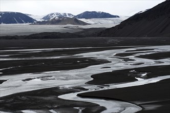 Meandering river in front of mountains and a glacial landscape