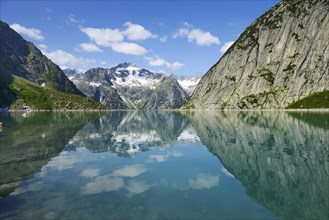 Mountains around the Grimsel Pass are reflected in Gelmerstausee reservoir