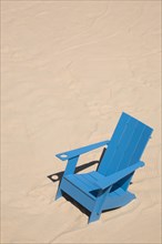 Blue adirondack chair standing on a beach