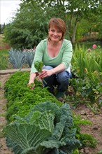Woman in a garden between cabbage plants
