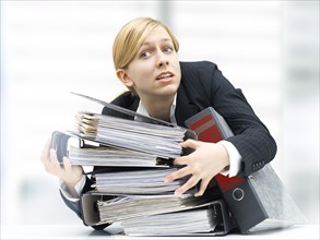 Stressed business woman holding a stack of folders
