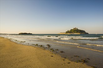 Sand beach with the island of St. Michael's Mount at high tide
