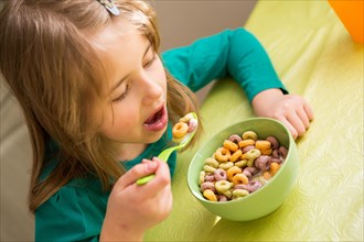 young girl eating cornflakes from the bowl